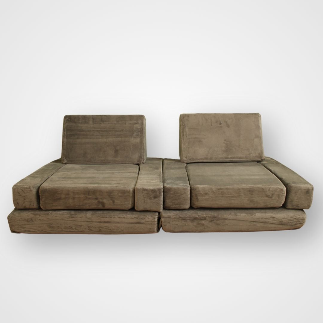 A modular play couch made up of multiple grey cushions, arranged in a configurable play space. Modular therapy cushions stacked in play couch configuration – soft, supportive setup for movement, rest, and creative exploration.