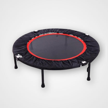 A round therapeutic rebounder with a black padding cover, red trim, and attached to black metal frame with visible springs. Therapeutic rebounder mini trampoline with stable frame – designed for kids to support coordination, balance, and active regulation.
